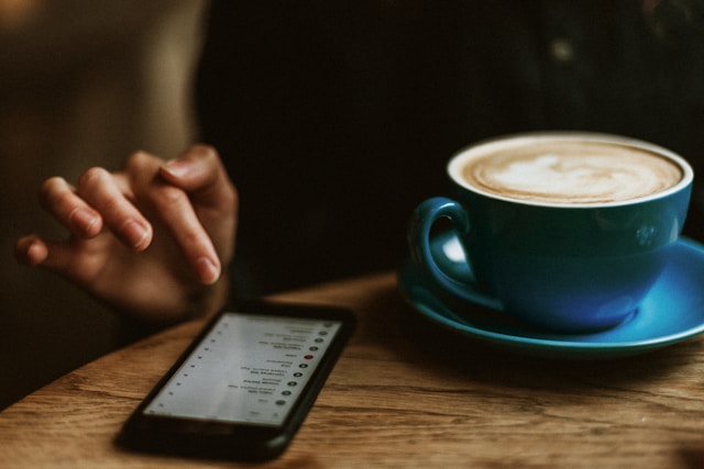 コーヒーを飲みながらスマートフォンを触る女性