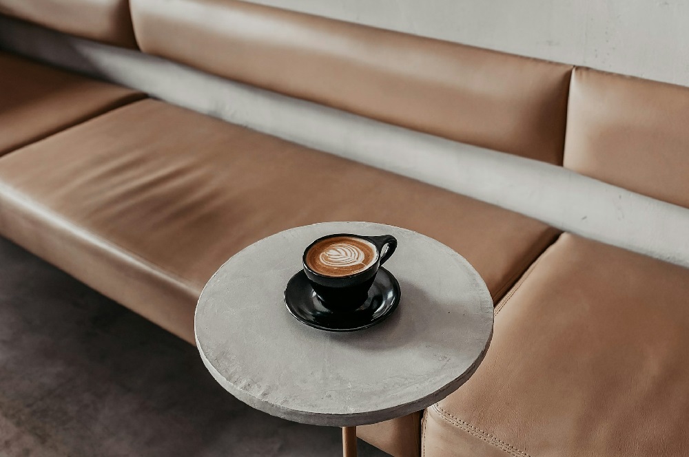 一人暮らしの自分時間をイメージした茶色いソファと丸いテーブルの上のカフェラテ